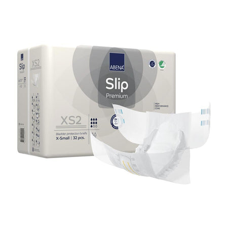 Ein Packung Abena Slip Premium XS2, eine hochwertige, anatomisch geformte Inkontinenzauflage für Erwachsene, liegt auf einem neutralen Untergrund. Die Verpackung zeigt ein modernes, ansprechendes Design mit einem klaren Produktnamen und wichtigen Symbolen, wie beispielsweise der Größe XS sowie der Saugstärke. Die Farben sind vorwiegend Weiß und Blau, während die Verpackung einen transparenten Bereich aufweist, der das Produkt sichtbar macht.