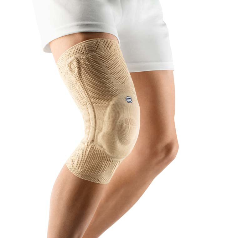 Bild von der Bauerfeind Genutrain Kniebandage in natürlicher Farbe. Die Bandage besteht aus einem flexiblen, atmungsaktiven Material und zeigt eine anatomische Form, die sich an das Knie anpasst. An der Vorderseite ist ein gepolstertes Gelenkelement sichtbar, das den Knieschutz verstärkt. Die äußeren Kanten der Bandage sind in einer kontrastierenden Farbe abgesetzt.