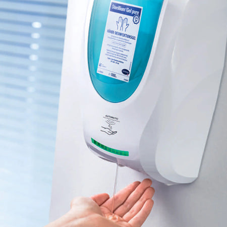 Desinfektionsmittelspender mit Sensor im modernen Design, in weißer Farbe. Der Spender ist für Wandmontage konzipiert und verfügt über einen transparenten Behälter zur einfachen Identifizierung des Füllstands. Der Sensor ermöglicht eine berührungslose Anwendung, ideal für die Handhygiene. Auf der Vorderseite des Spenders ist ein Bedienfeld mit einem klaren Sichtfenster sichtbar. Die Konstruktion ist aus robustem Material, das eine lange Lebensdauer verspricht.