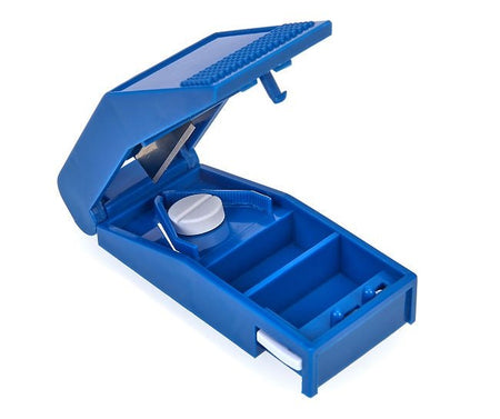 Ein Pillenschneider in einer klaren, modernen Gestaltung aus robustem Kunststoff. Die Hauptfarbe ist ein ansprechendes Grau mit einem transparenten Deckel, der eine Sicht auf die Klingen im Inneren ermöglicht. Der Schneider hat eine ergonomische Form, die eine einfache Handhabung gewährleistet. Die Klingen sind scharf und präzise, um Medikamente gleichmäßig zu schneiden. Auf der Oberseite befindet sich eine praktische Drucktaste zur Betätigung.