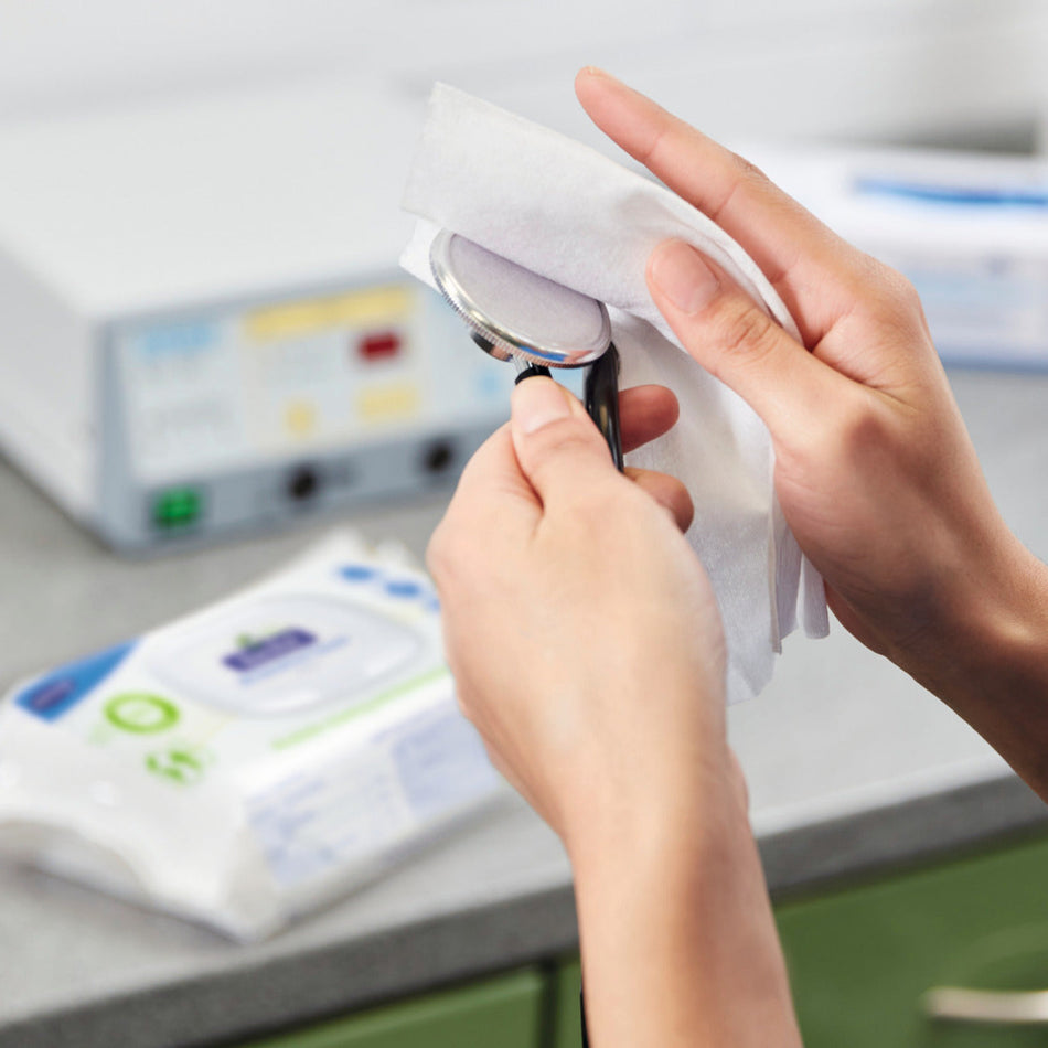 Anwendung der Bacillol 30 Sensitive Green Tissues – Person reinigt ein medizinisches Instrument mit einem Tuch in einer klinischen Umgebung.