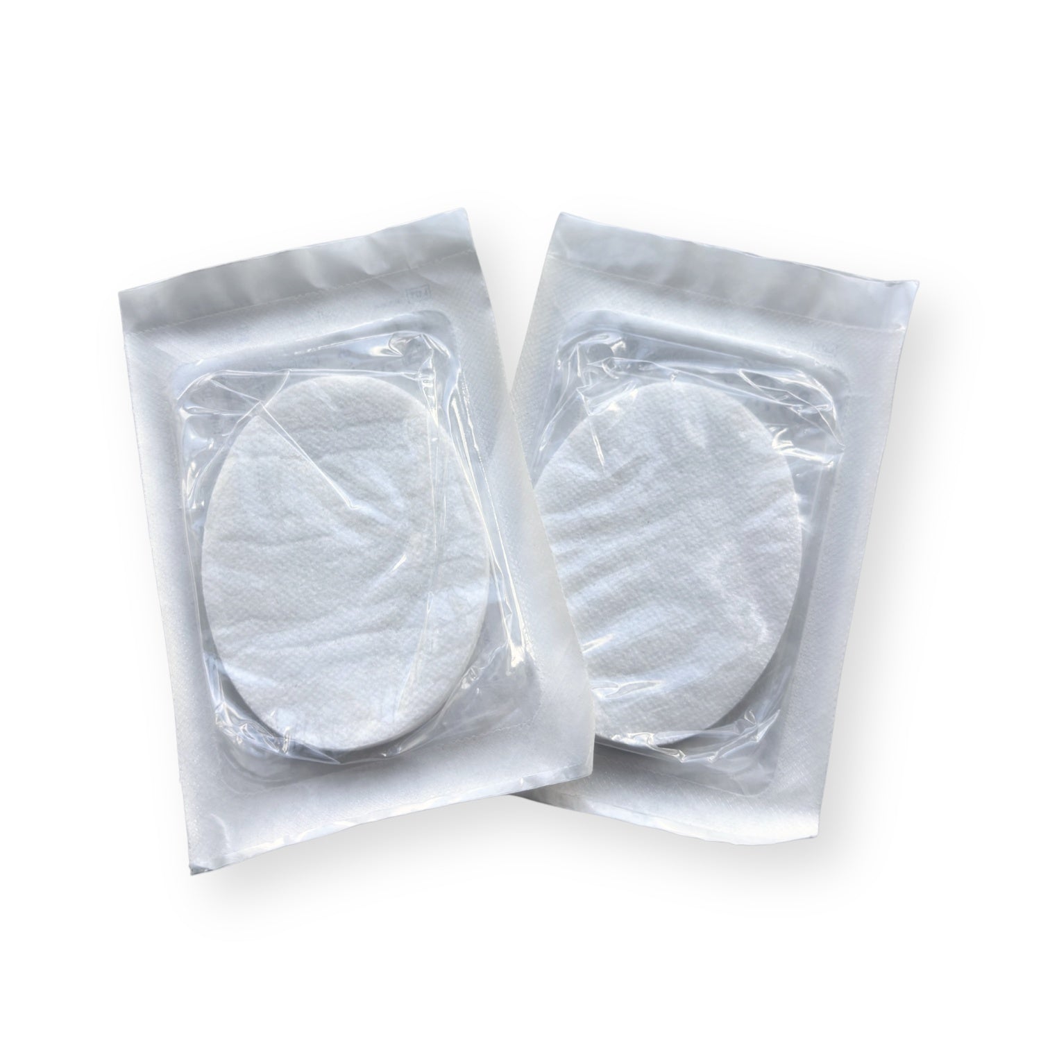 Zwei steril verpackte ovale Augenkompressen in Einzelverpackung auf hellem Hintergrund.