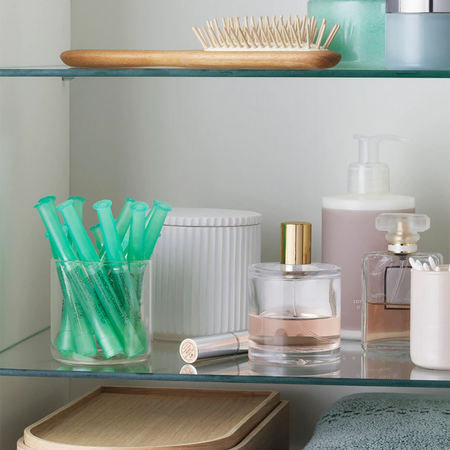 SpeediCath Katheter für Frauen, zu sehen in einem Glas im Waschbeckenschrank in einem Badezimmer.