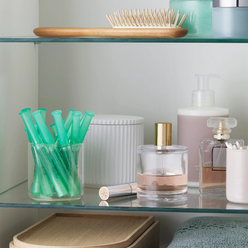 SpeediCath Katheter für Frauen, zu sehen in einem Glas im Waschbeckenschrank in einem Badezimmer.